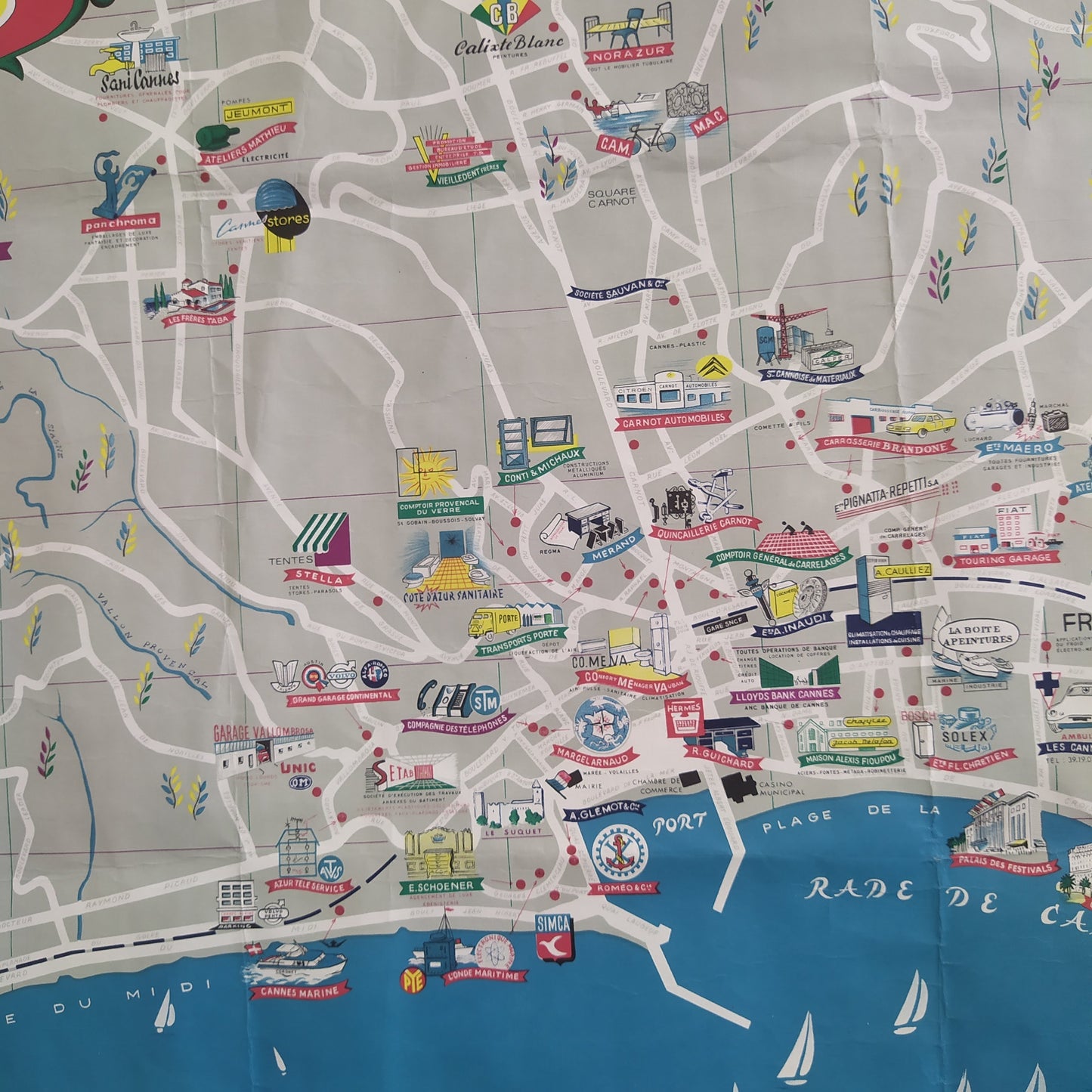 Carte géographique illustrée de la ville de Cannes vue d'ensemble, avec son encadrement rouge et vert, et la légende Cannes - Le Port et les Industries au style rétro par Jorj Morin (ca. 1960).