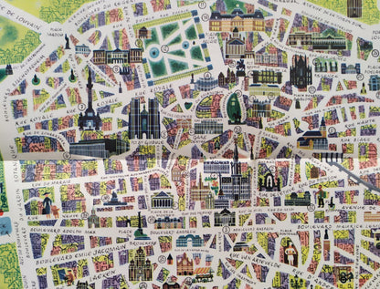 Gros plan sur le centre-ville montrant le tracé des rues et les façades des bâtiments historiques dessinés dans un style artistique avec des touches de rose, bleu et vert.
