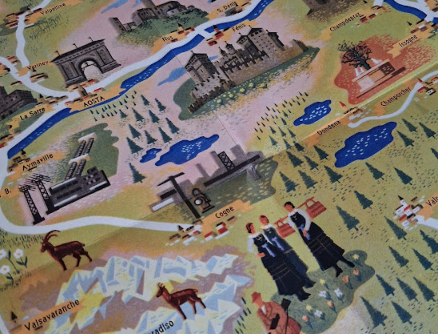 Gros plan sur la partie centrale de la carte montrant la ville d'Aoste, l'Arc d'Auguste, des châteaux (Fénis), des usines, la rivière et des illustrations de personnes en costumes traditionnels.