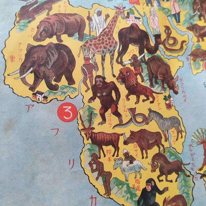 Zoom sur le continent africain sur la carte japonaise, illustré avec des éléphants, girafes, lions, et des représentations de peuples africains.