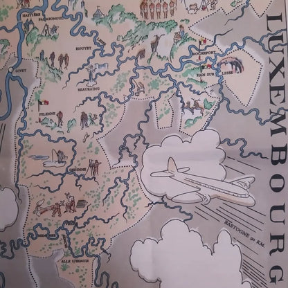 Gros plan sur la partie supérieure d'une carte illustrée et vintage du Pays de Namur, mettant en évidence le titre et l'illustration d'un homme écrivant sur un tombeau. Le détail montre les villes de Namur, Huy, Dinant, Charleroi, et le tracé des rivières Sambre et Meuse.