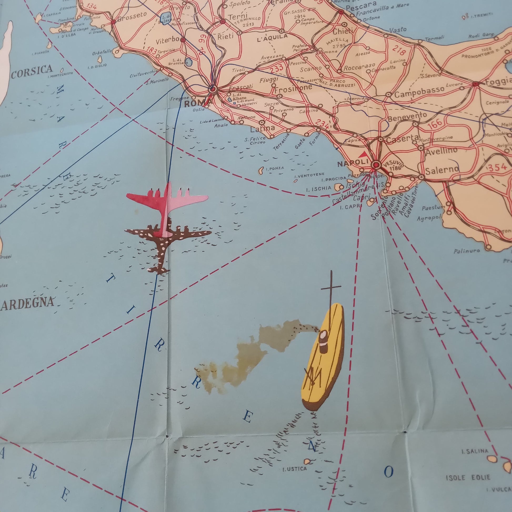 Gros plan sur la partie centrale d'une carte vintage et illustrée de l'Italie de 1953. L'image est centrée sur la zone de Rome et de Naples, montrant les réseaux routiers et ferroviaires en rouge. Un avion rose et un navire jaune avec une cheminée fumante sont dessinés sur la mer Tyrrhénienne, symbolisant les liaisons aériennes et maritimes.