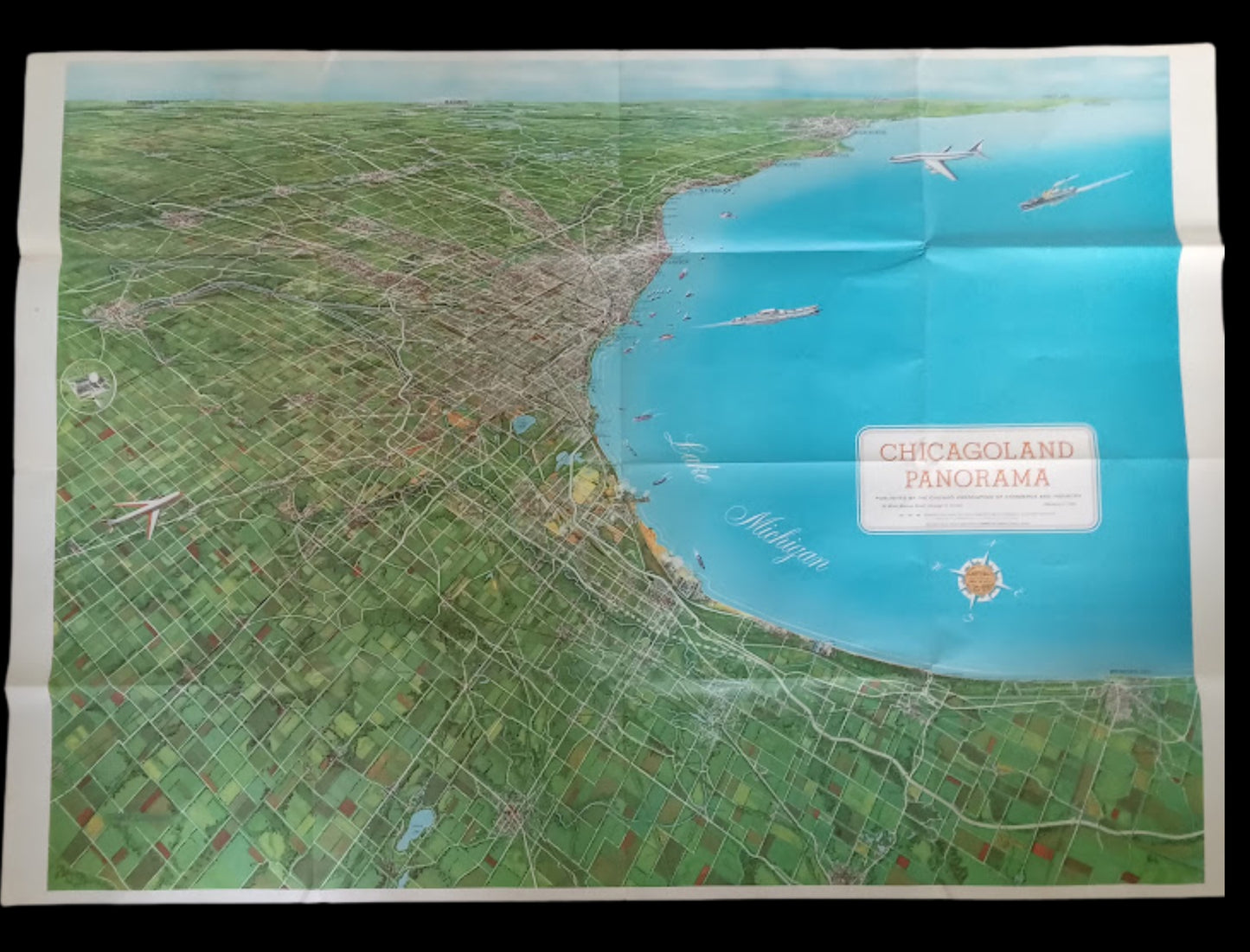 Vue d'ensemble d'une grande carte panoramique de la région de Chicago montrant l'étalement urbain vert à gauche et l'immensité bleue du lac Michigan à droite.
